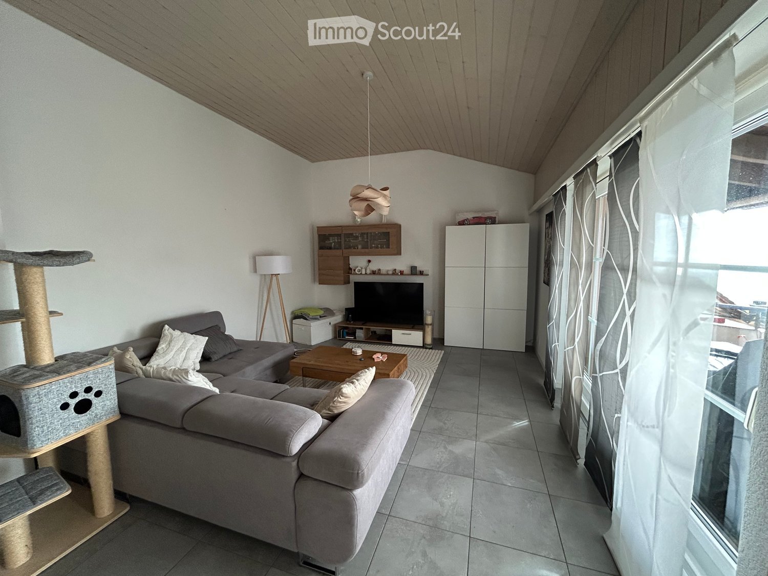 large sofa, TV stand, wooden floor, tall windows, cat tower