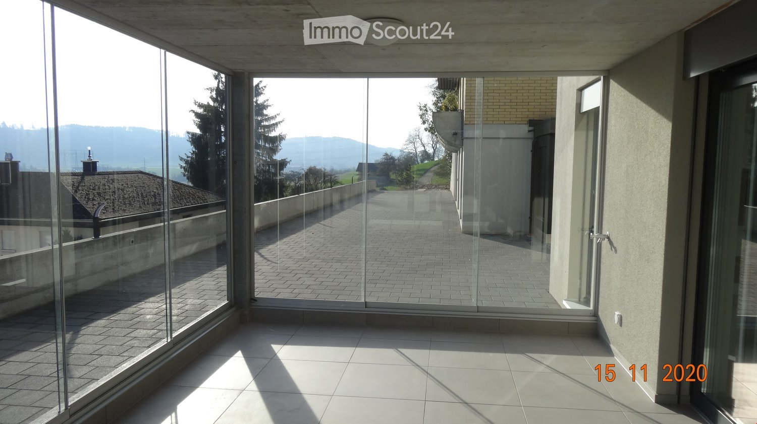 empty balcony, glass wall, tiled floor, wide angle view of the village and mountains
