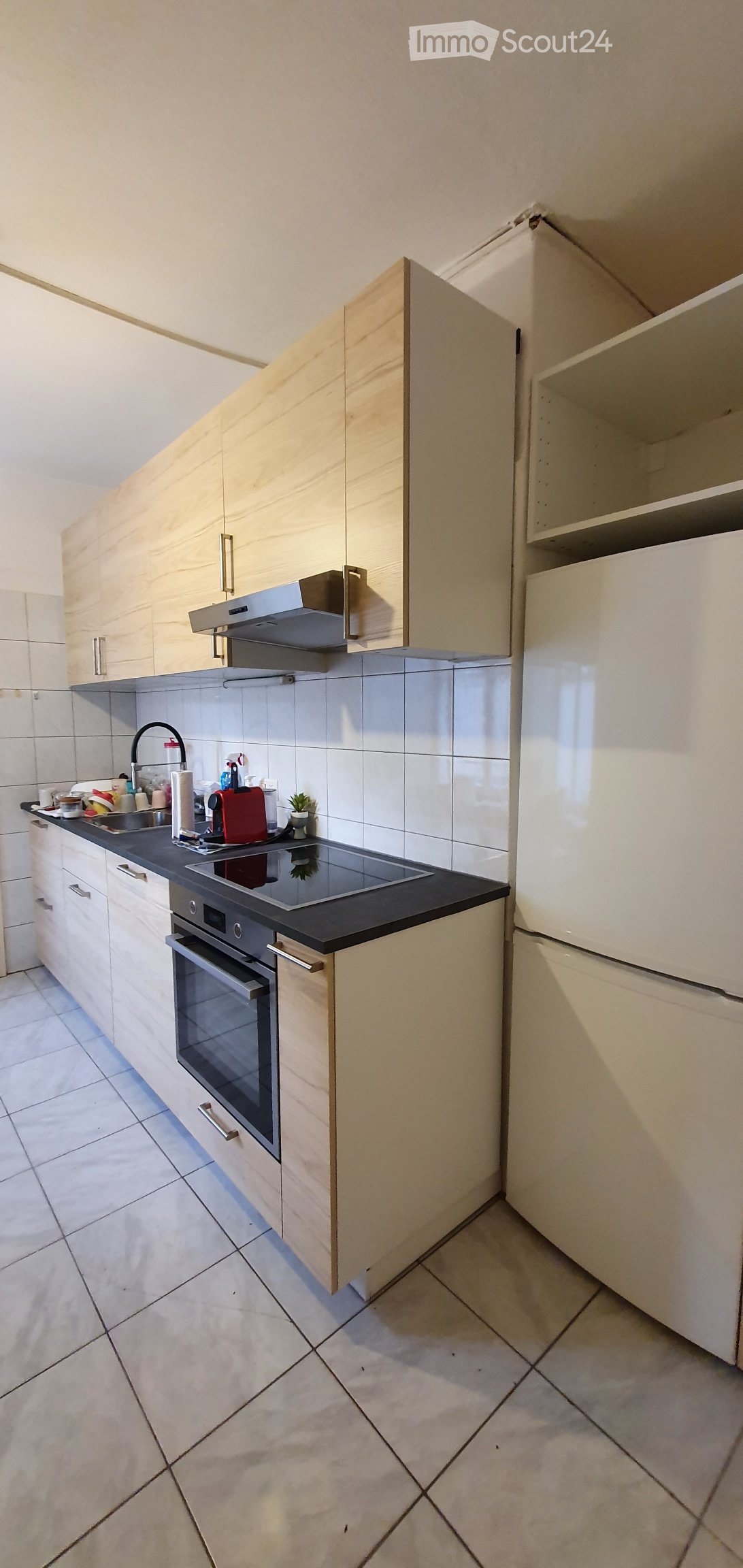 Wooden cabinets, white tiles, black countertop, oven, fridge, sink, faucet