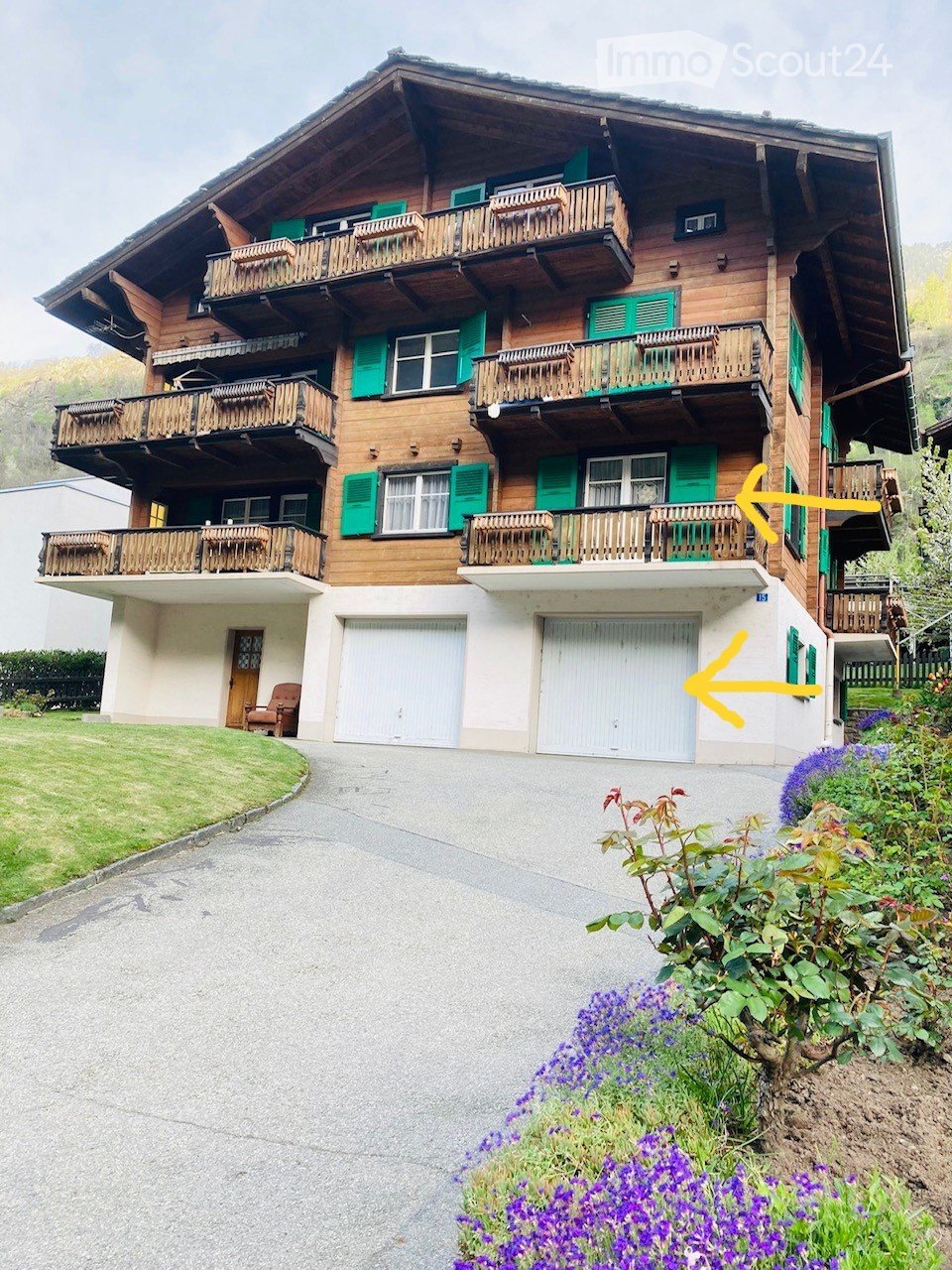 3 story building, wooden balconies, brown shutters, garage, front yard