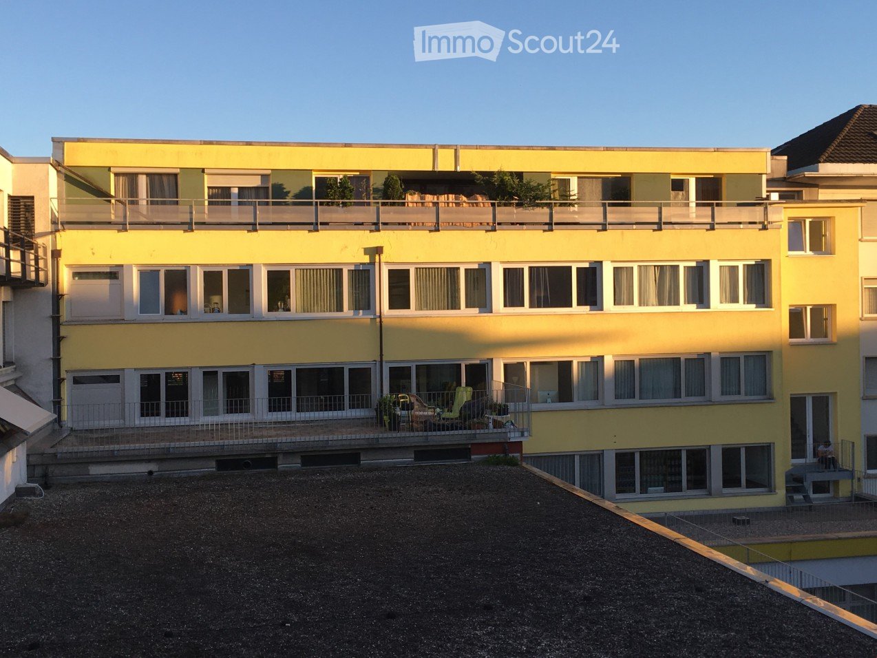 Yellow multi-story apartment building, multiple balconies, modern architecture