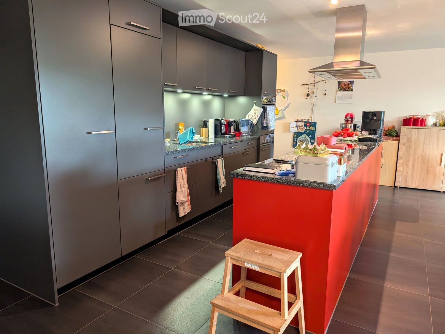 modern kitchen with built-in appliances, cabinets, central island, stove hood, tiled floor, step stool