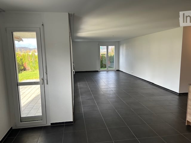 Empty room with white walls and black tiles on the floor, glass doors with white frames, no furniture