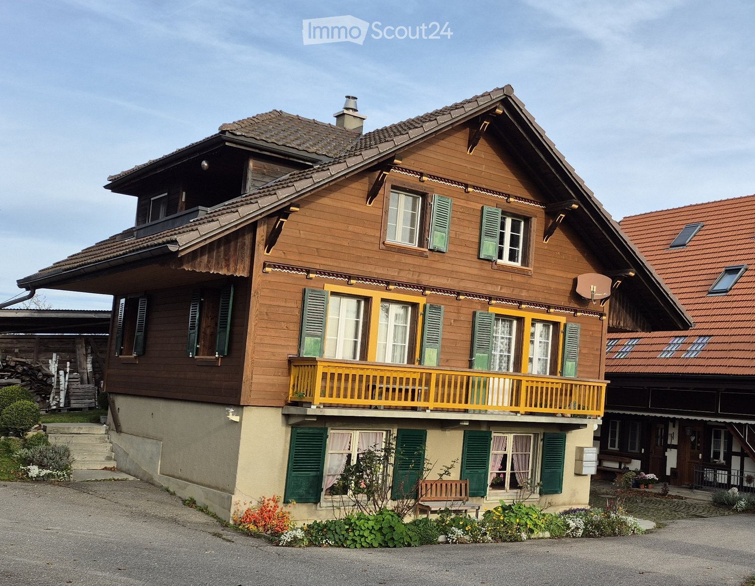 two story house, brown wooden wall, yellow balcony, green shutters, chimney, garden
