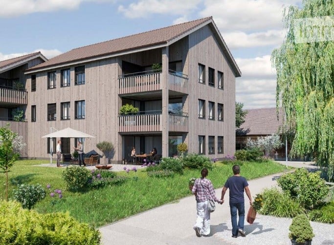 Wooden building, three stories, balconies, multiple windows, garden area with pathways, potted plants, and people walking