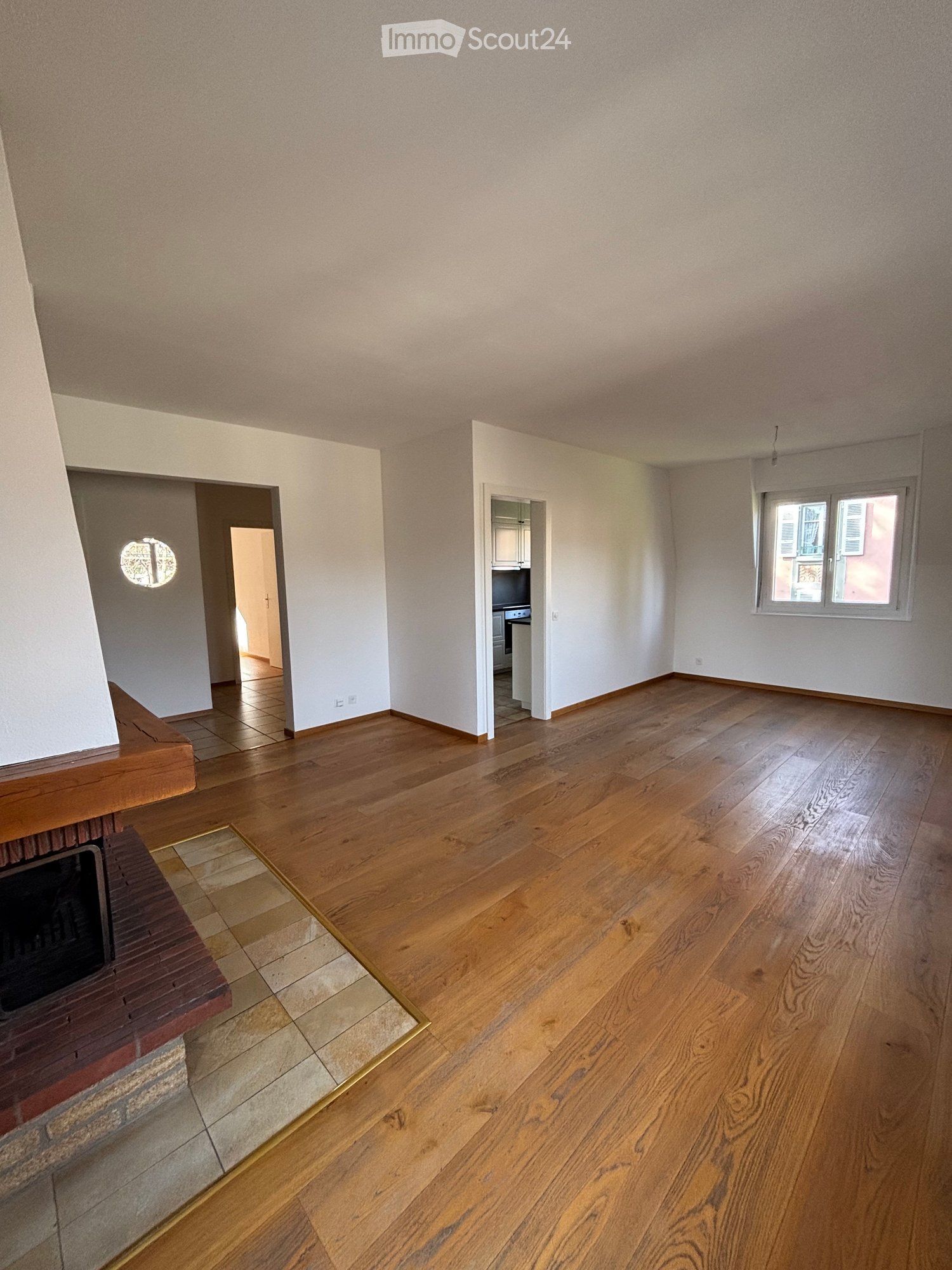 Fireplace, hardwood flooring, open room layout, windows, archway