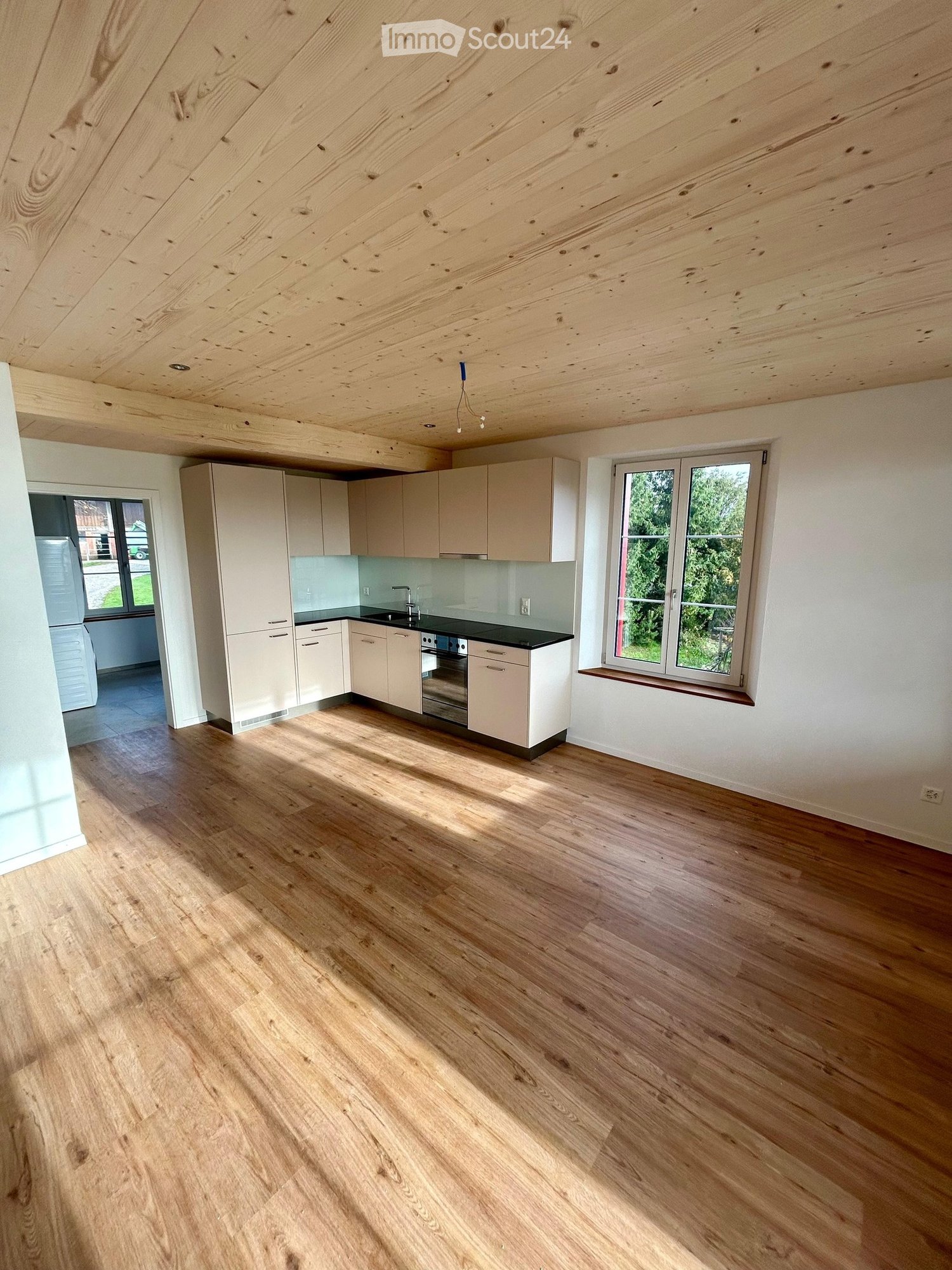 wooden floor, white walls, kitchen with white cabinets, window with wooden sill, stainless steel sink and faucet, electric oven, view of the outside