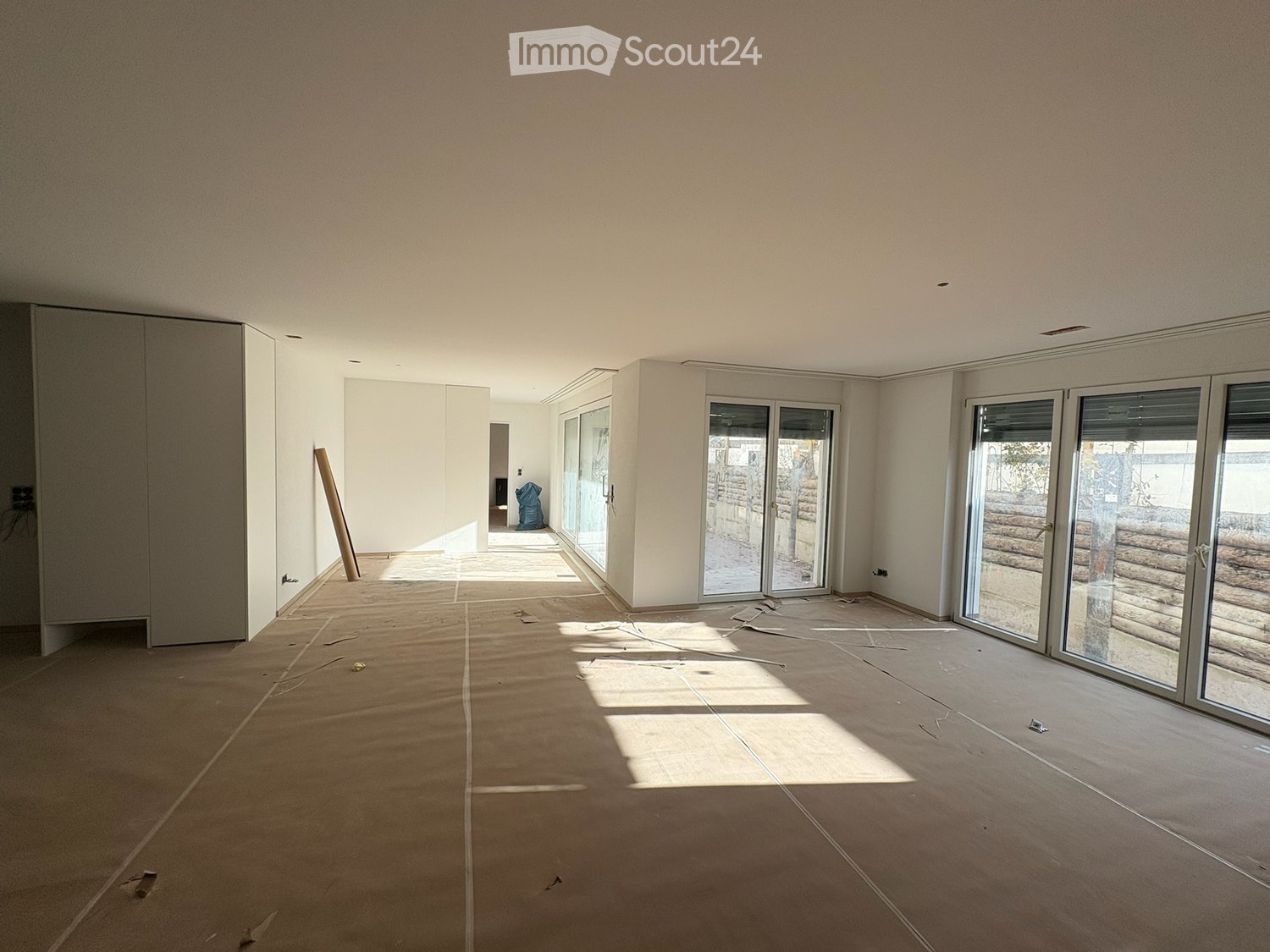 open room, white walls, large sliding glass doors, brown floor, closet