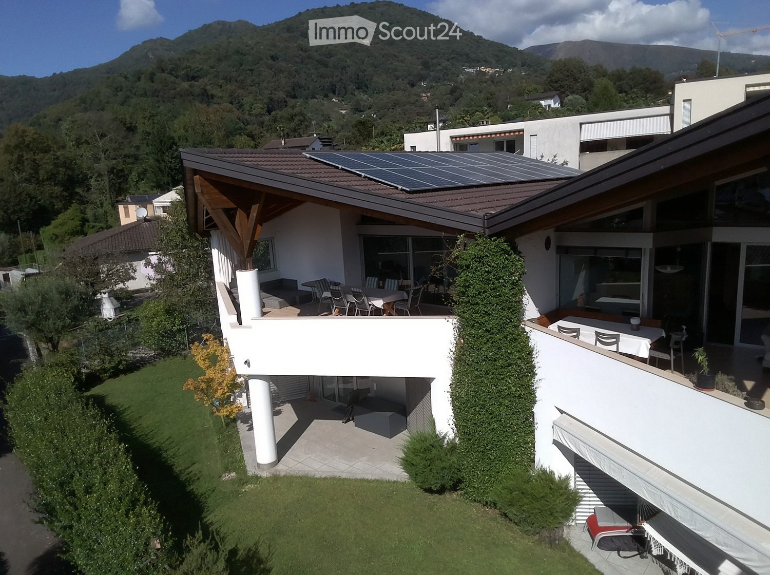 House with terrace, solar panels, surrounded by a well-maintained garden, mountain view