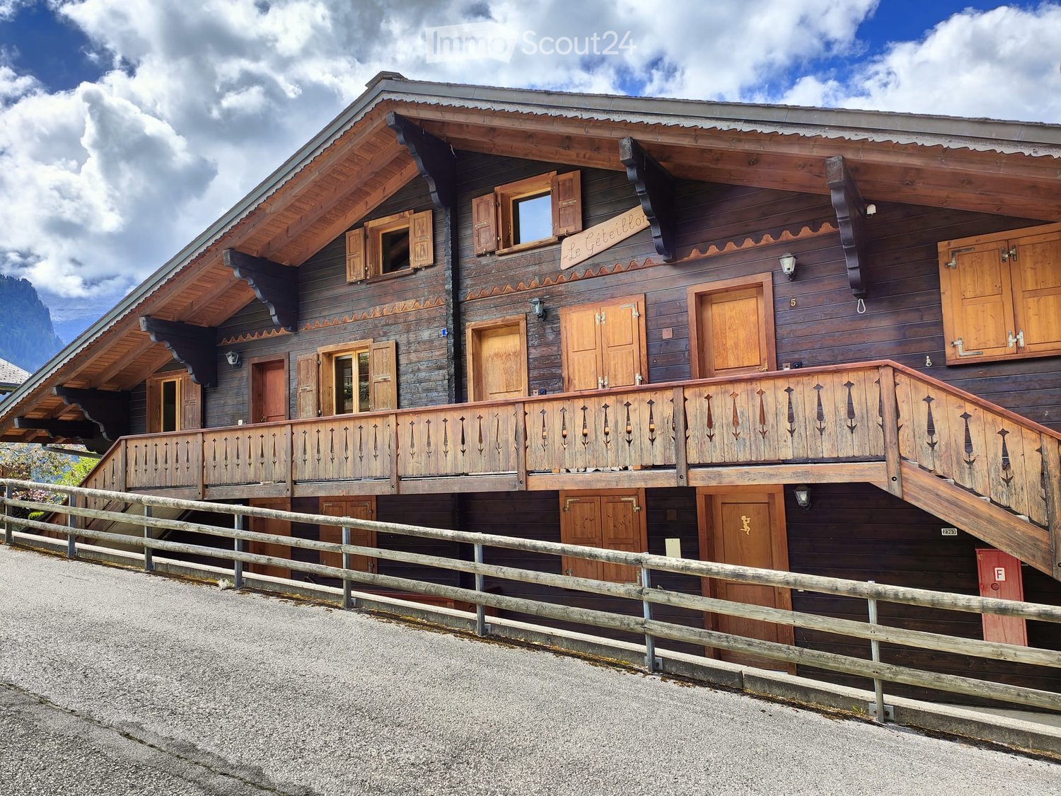 Alpine style wooden house, wooden balcony, multiple windows, wooden shutters, sign 'Le Geteillo'