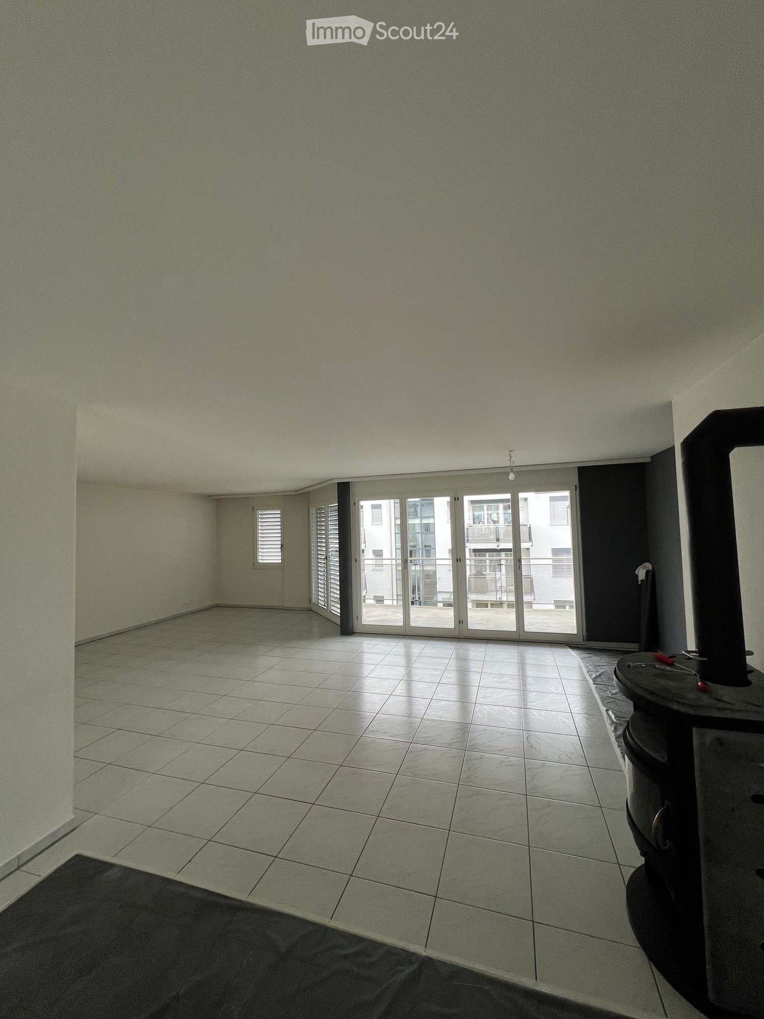 modern room with white tiled floor, white walls, sliding glass doors with balcony