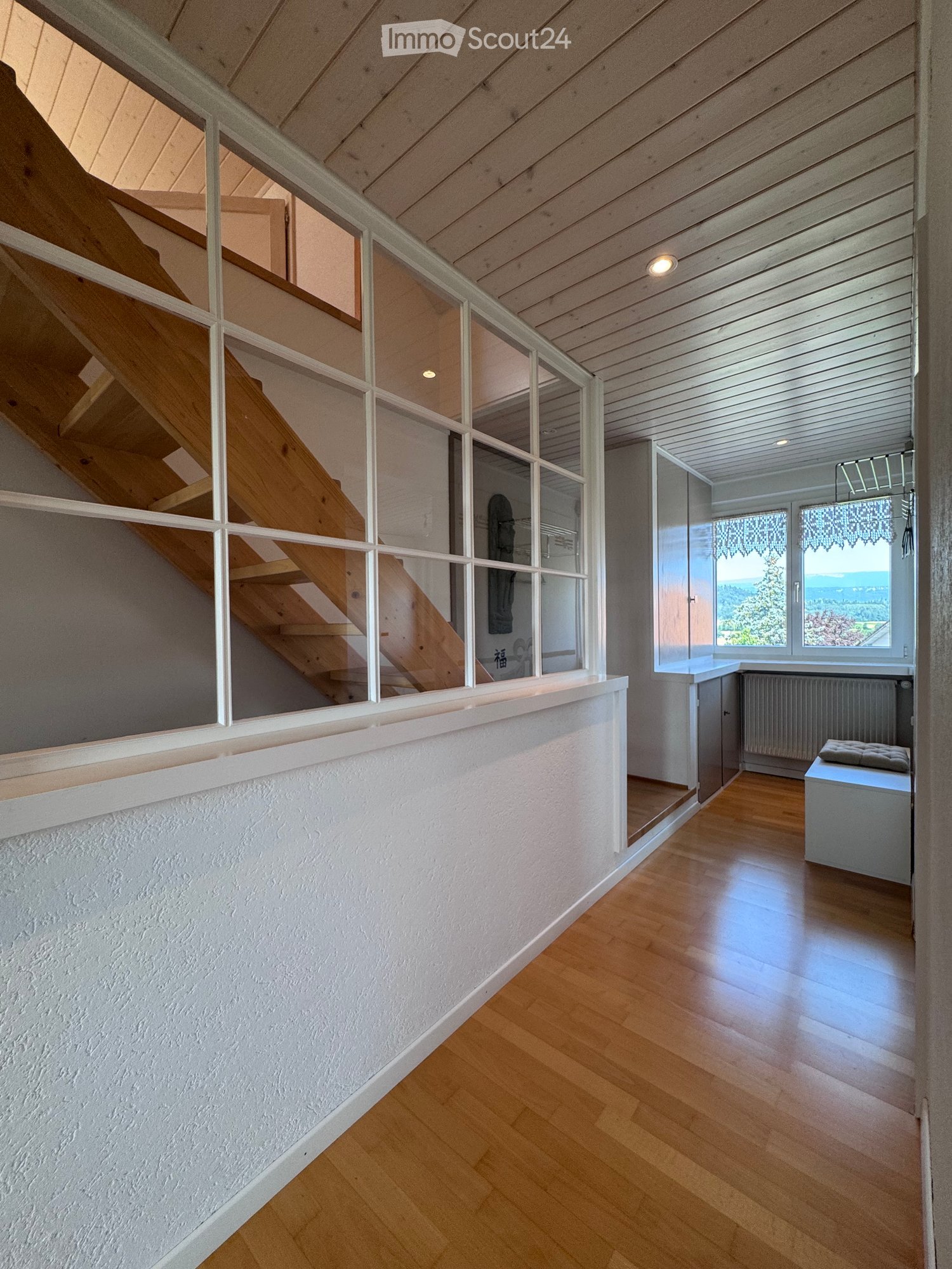 corridor with wooden floor, white walls, large glass window, wooden staircase, radiator