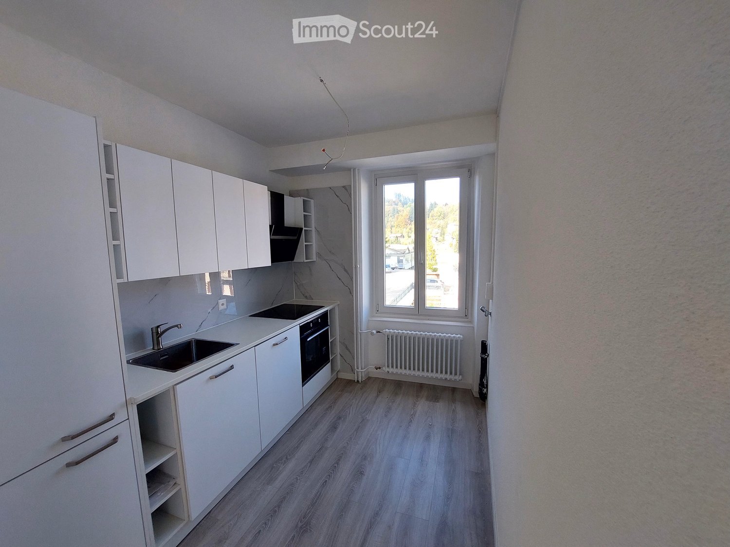 modern kitchen with white cabinets, black induction stove, black sink, wooden floor, white tiles