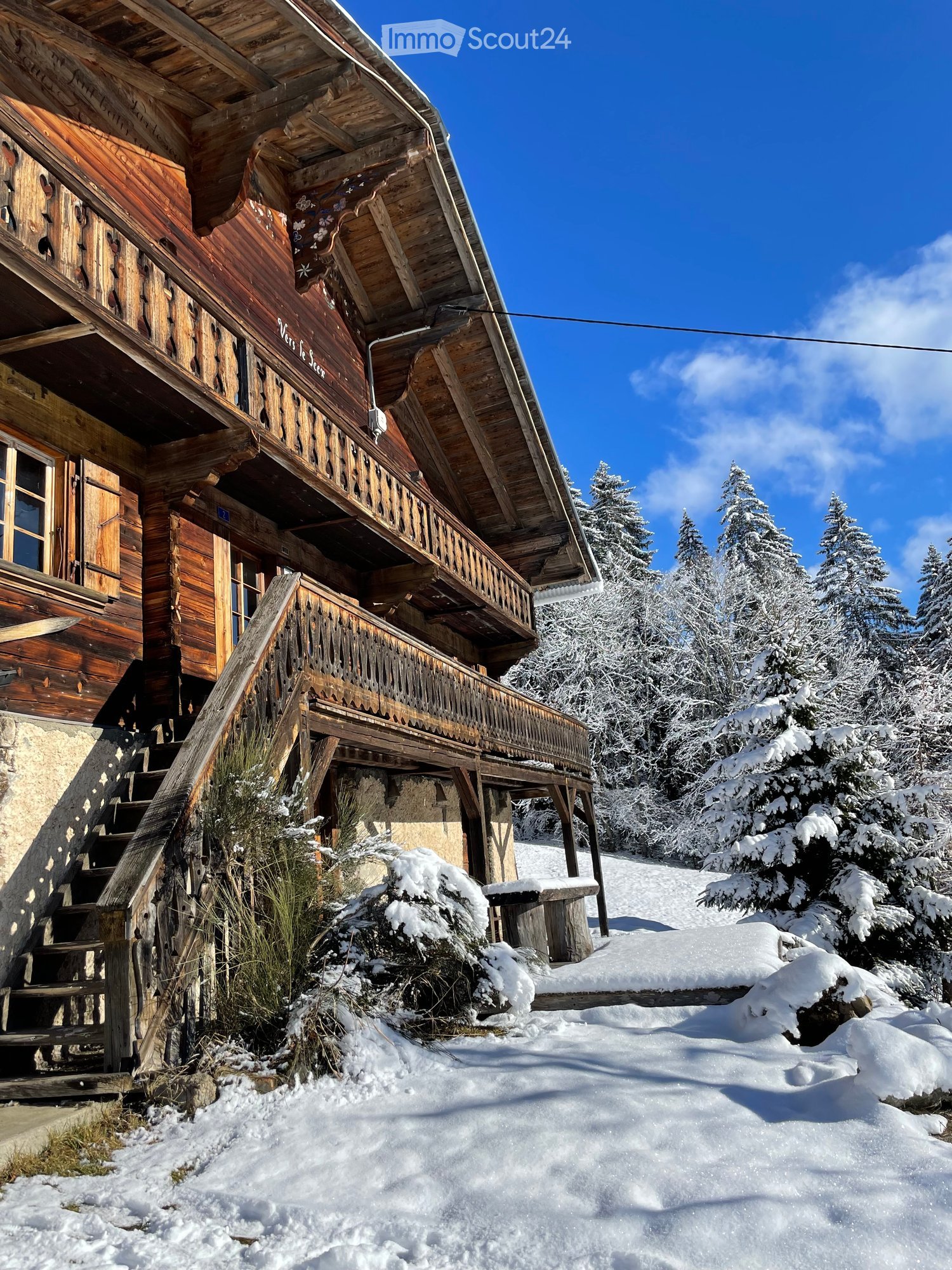 wooden chalet, covered balcony, snowy environment, stone foundation, snow on the ground, wooden stairs