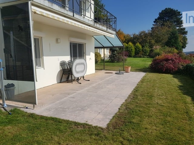 white house, balcony, glass door, chairs, table, green grass, trees