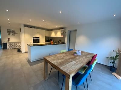 modern dining room with a dining table, white walls, wooden flooring, kitchen, cabinets, ceiling light