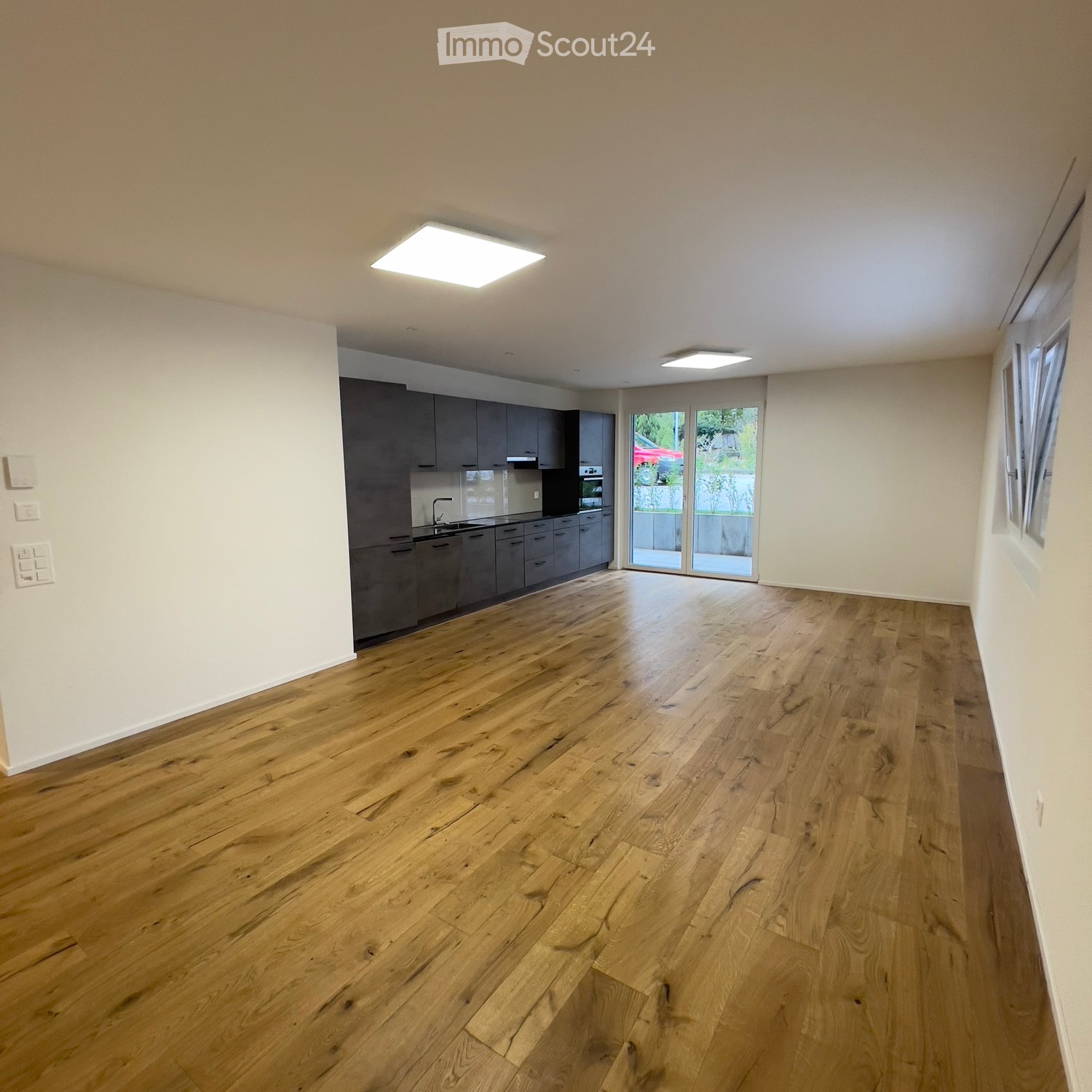 empty room, wooden floor, grey cabinets, sliding glass door to outside, square recessed ceiling lights