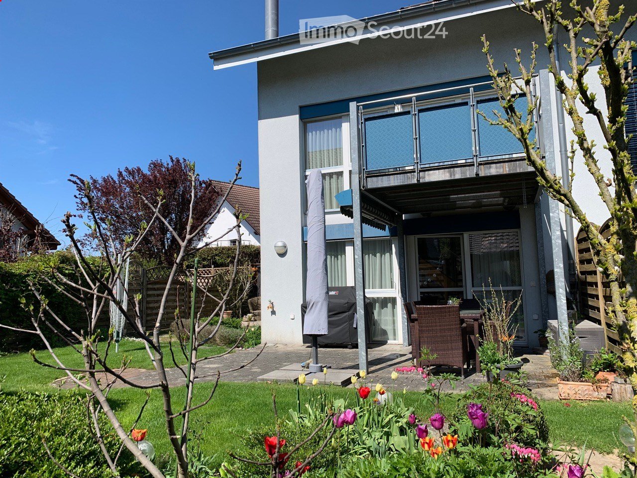 2-storey house, white exterior, grey garage cover, well-maintained garden, balcony, outdoor dining table and chairs