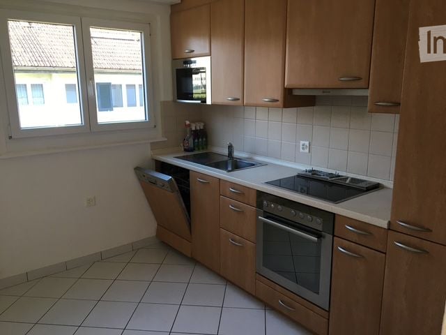 modern kitchen, window, dishwasher, washing machine, gas stove, built-in oven, white tiles, wooden cabinets, sink, faucet, view of the street