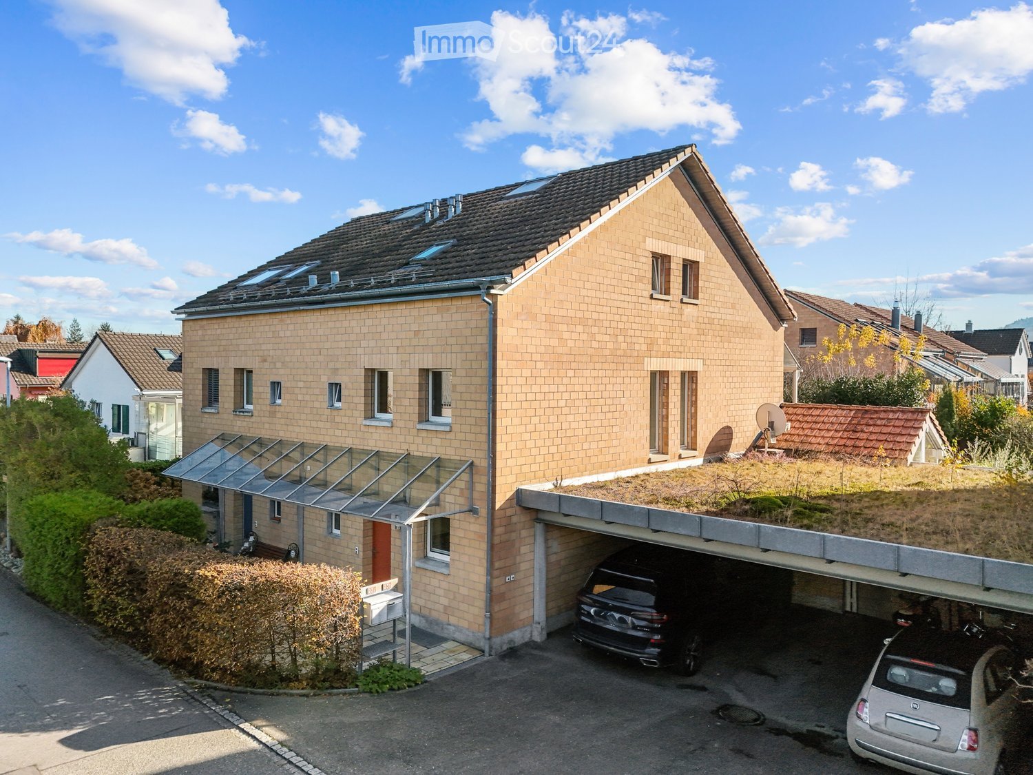 Two story house, brick wall, solar panels, attached garage, two cars parked in garage