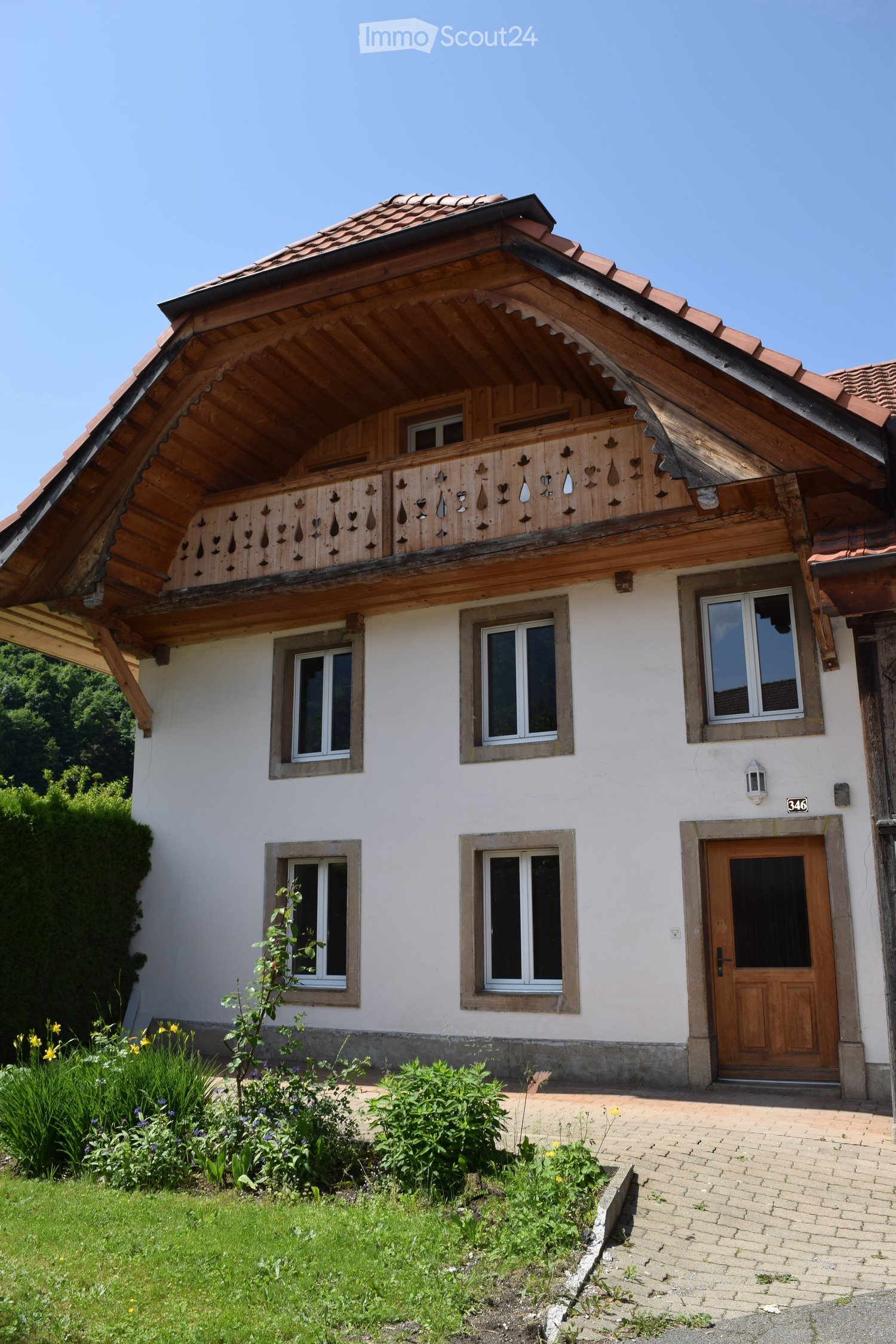white stucco house, brown roof, wooden balcony, wooden door