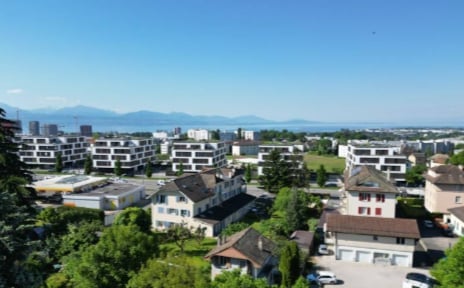 urban area with various buildings, including apartments and houses, green trees, and clear blue sky