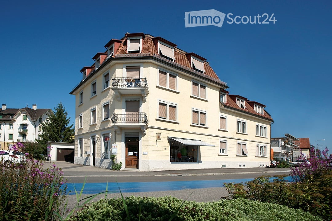 3 story building, white exterior, brown roof, balconies, garage, storefront window