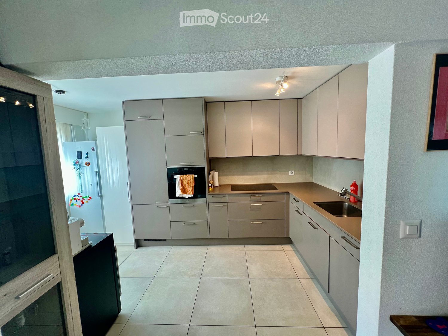 modern gray cabinets, tiled floor, granite countertop, stainless steel sink, oven, refrigerator, built-in dishwasher, modern lighting