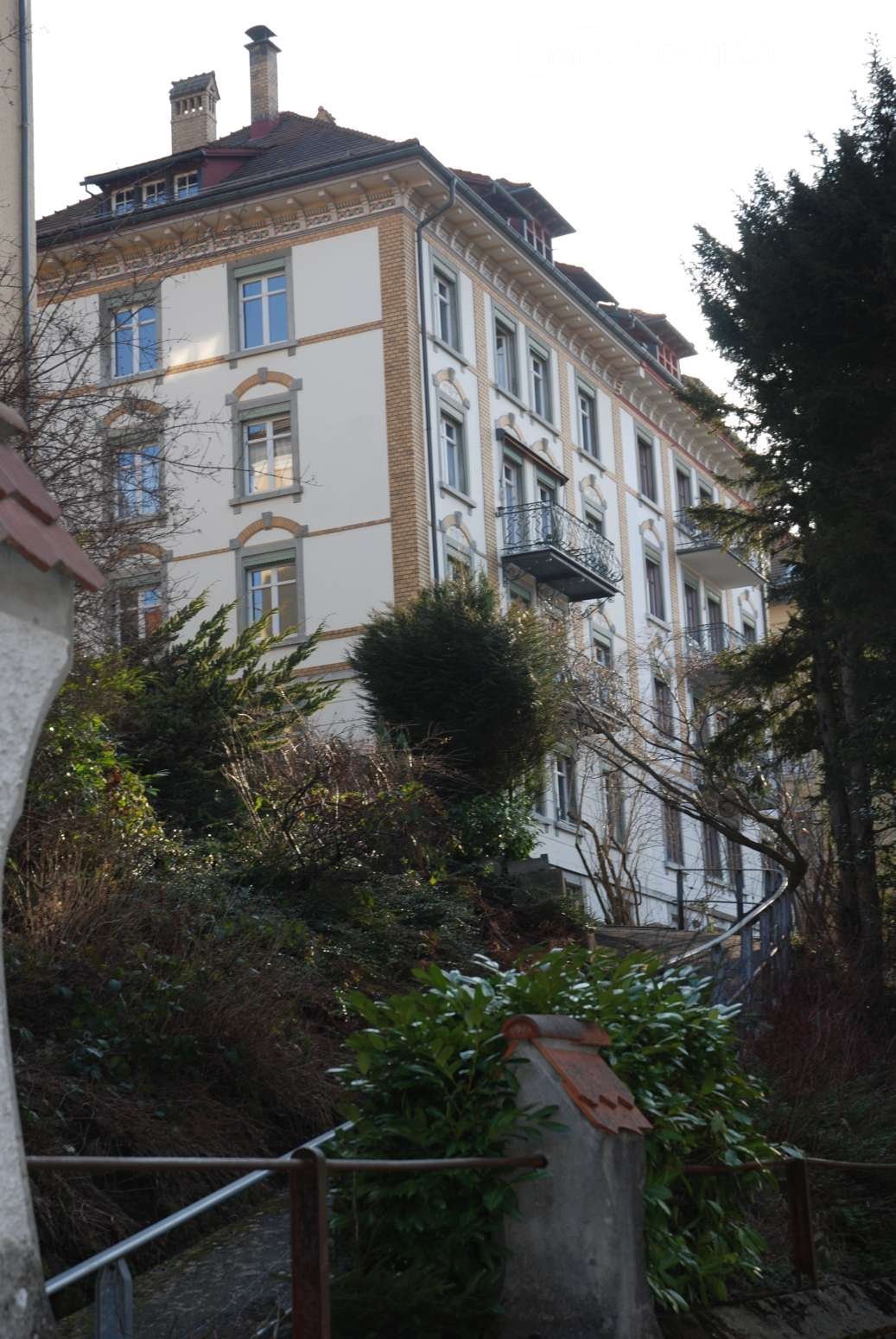 3 story building, white walls, red brick, many windows, balcony