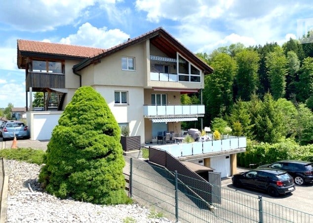2 story house, tan exterior, red roof, 2 balconies, 3 cars parked, fenced yard
