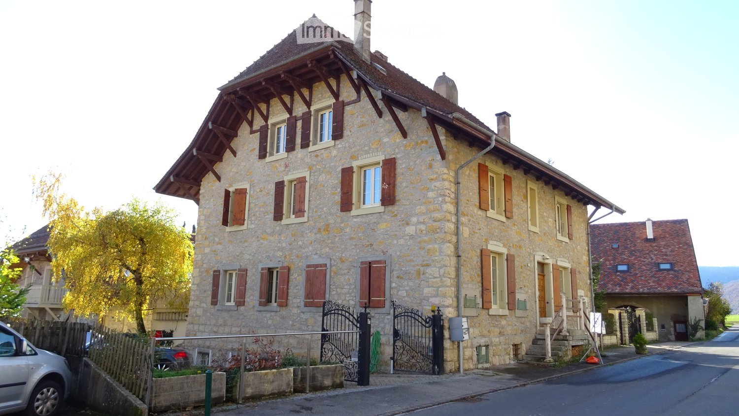 Stone building, 3 stories, wooden doors, balconies, garage, tree, parked cars