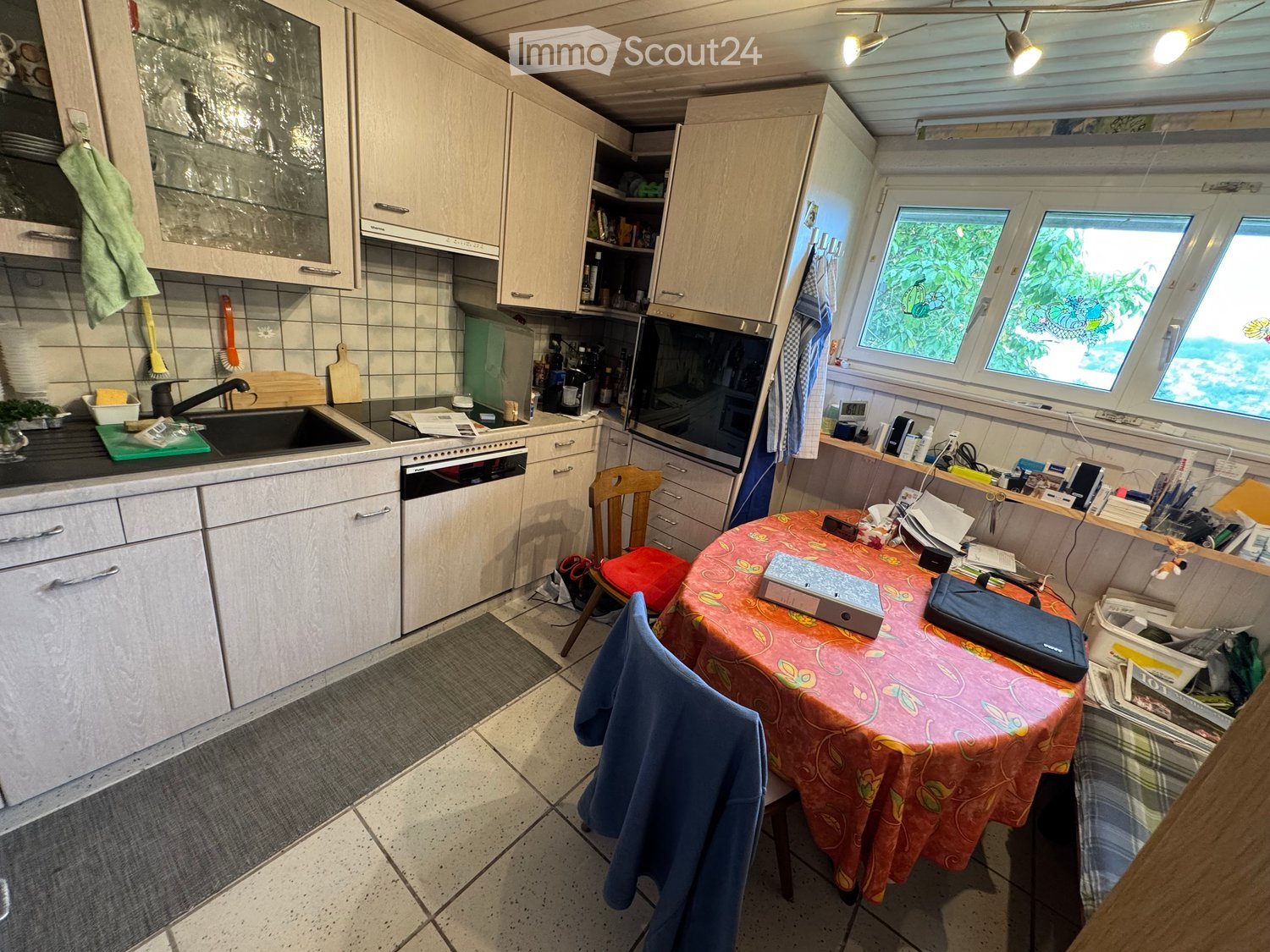 kitchen with tile floor, white cabinets, sink, countertop, microwave, dishwasher, oven, windows, table with chairs