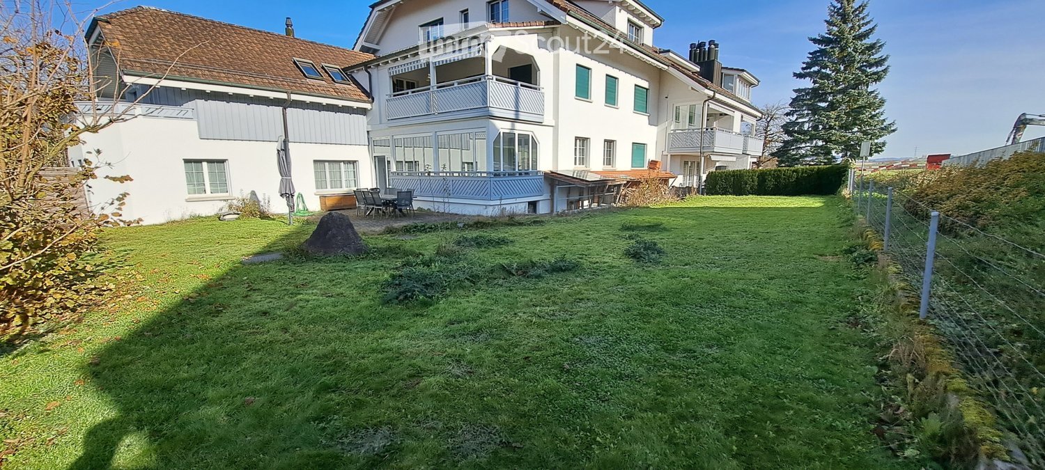 two-story house, brown roof, white exterior walls, large balcony, fenced yard, large green lawn