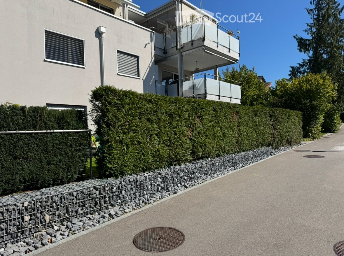 White house, modern design, with glass windows, a balcony with a glass railing, concrete pathway with manhole cover