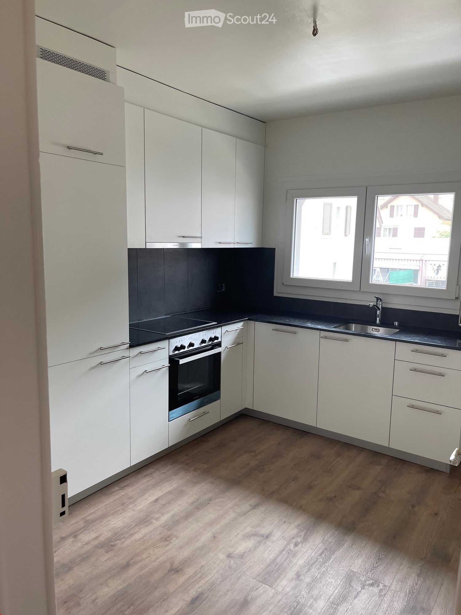 modern kitchen, white cabinets, black countertops, stainless steel appliances, wooden floor