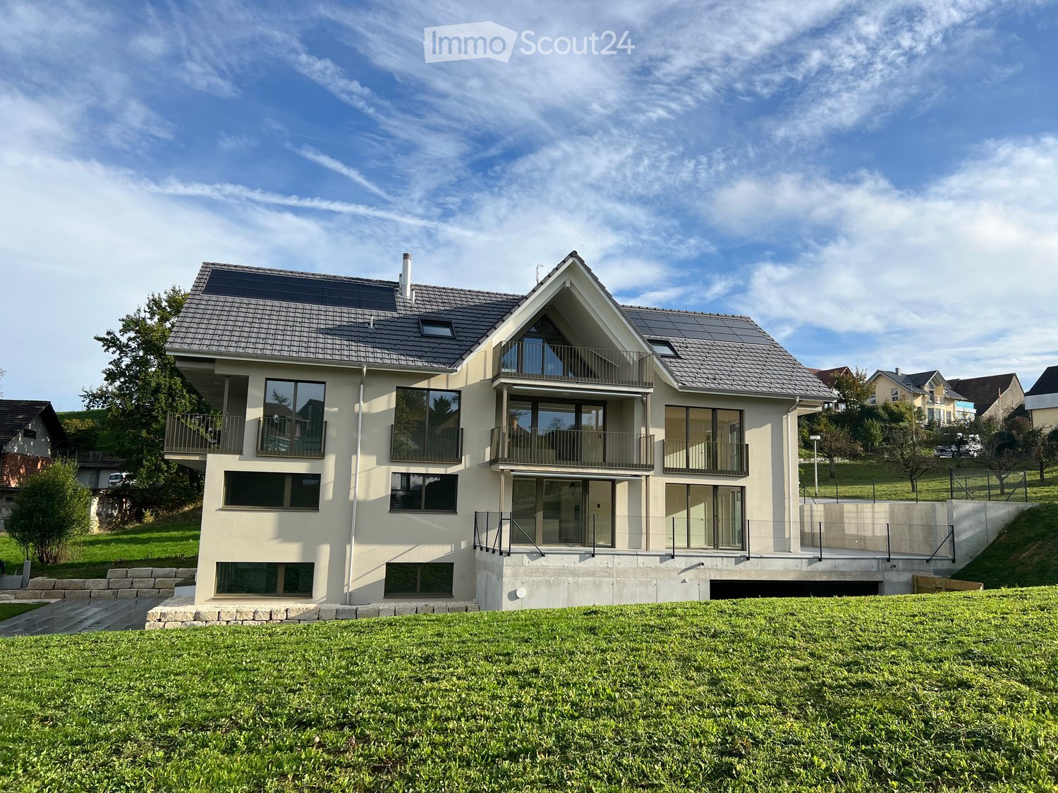 2-story modern house, beige walls, solar panels on the roof, balconies with railings, driveway