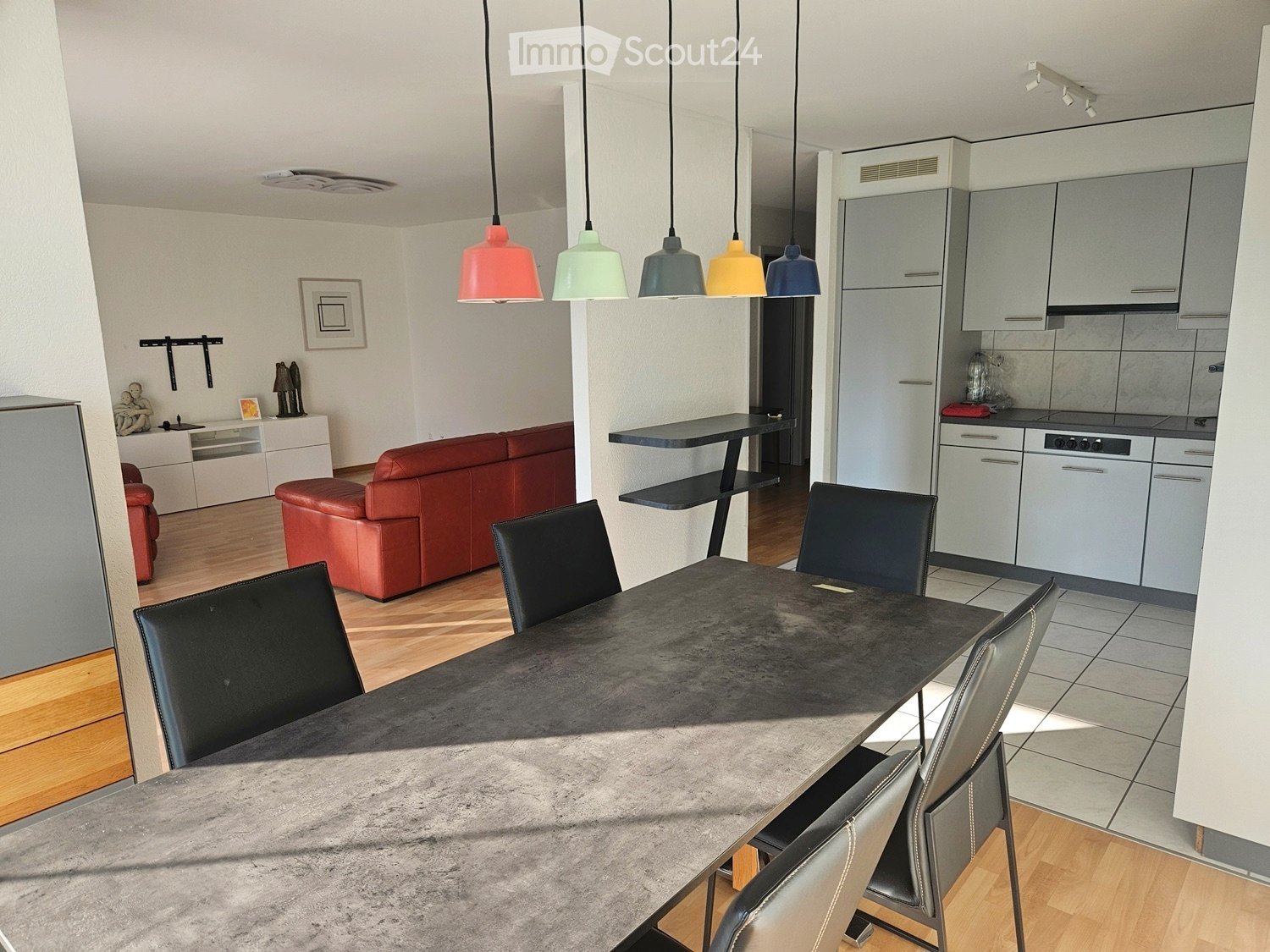 dining table, six chairs, wooden floor, kitchen open to dining, refrigerator, cabinets, gas stove, kitchen counter, colorful lamps, sofa, wall decorations