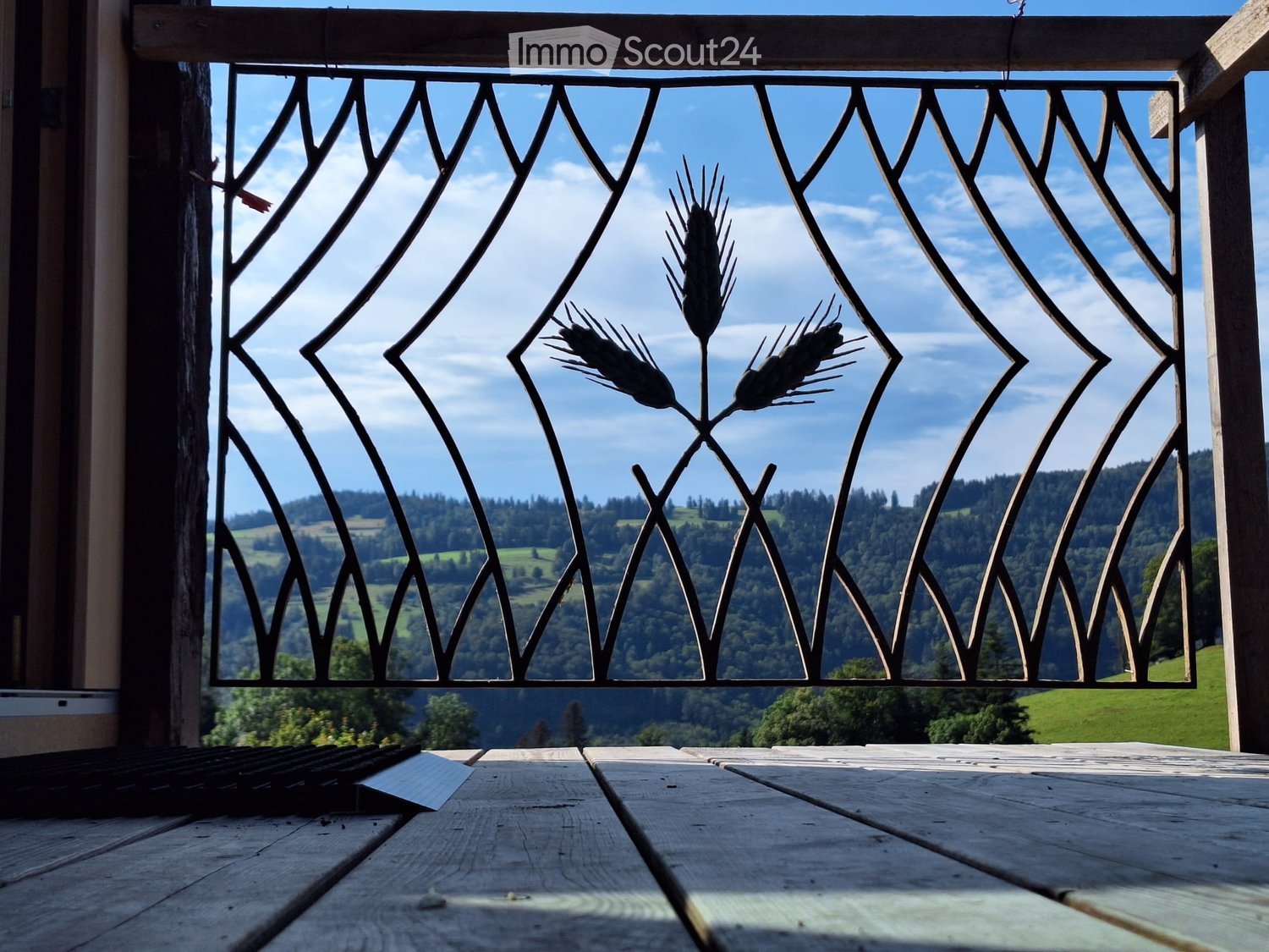 A metal gate on a balcony with a view of the mountains and blue sky