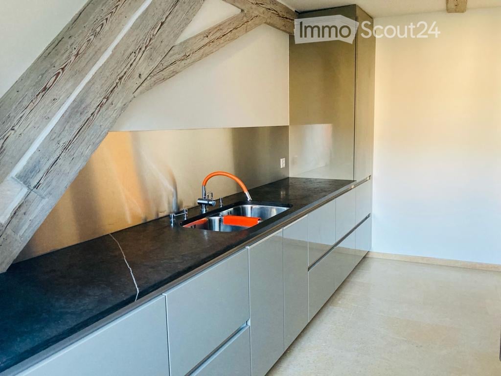 modern kitchen, black countertops, stainless steel appliances, wooden beams, orange faucet, sink, cabinets, tile flooring