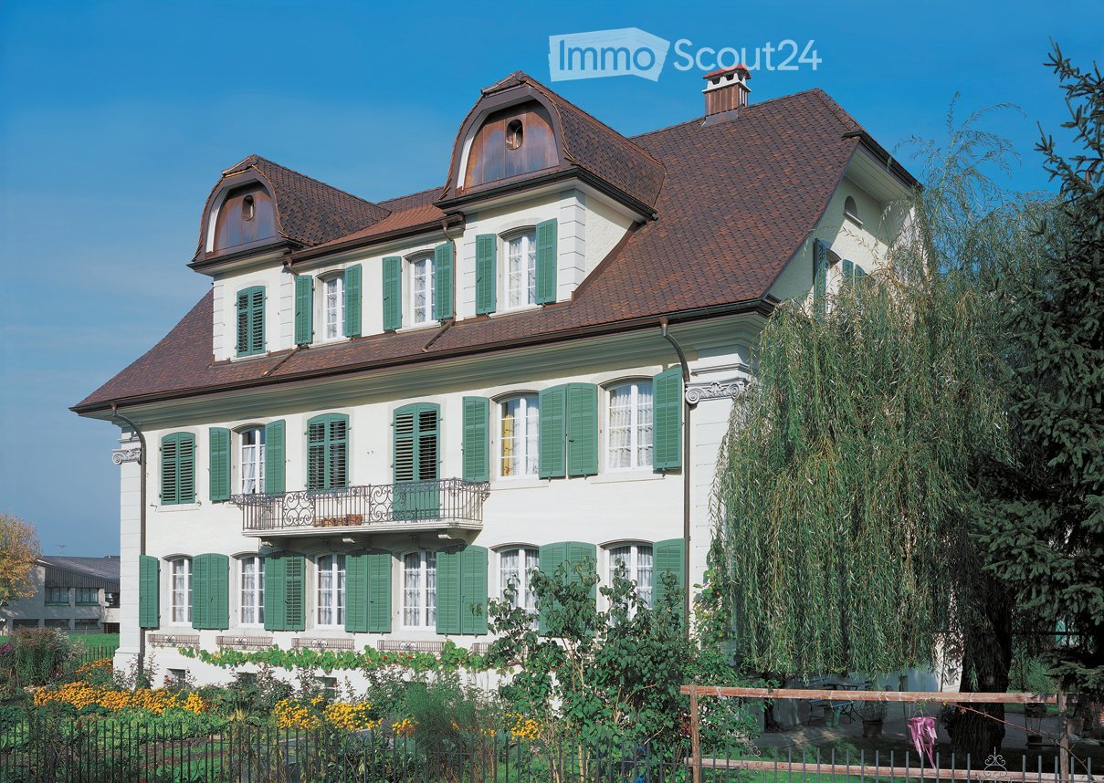 3 story white house, brown roof, green shutters, balcony