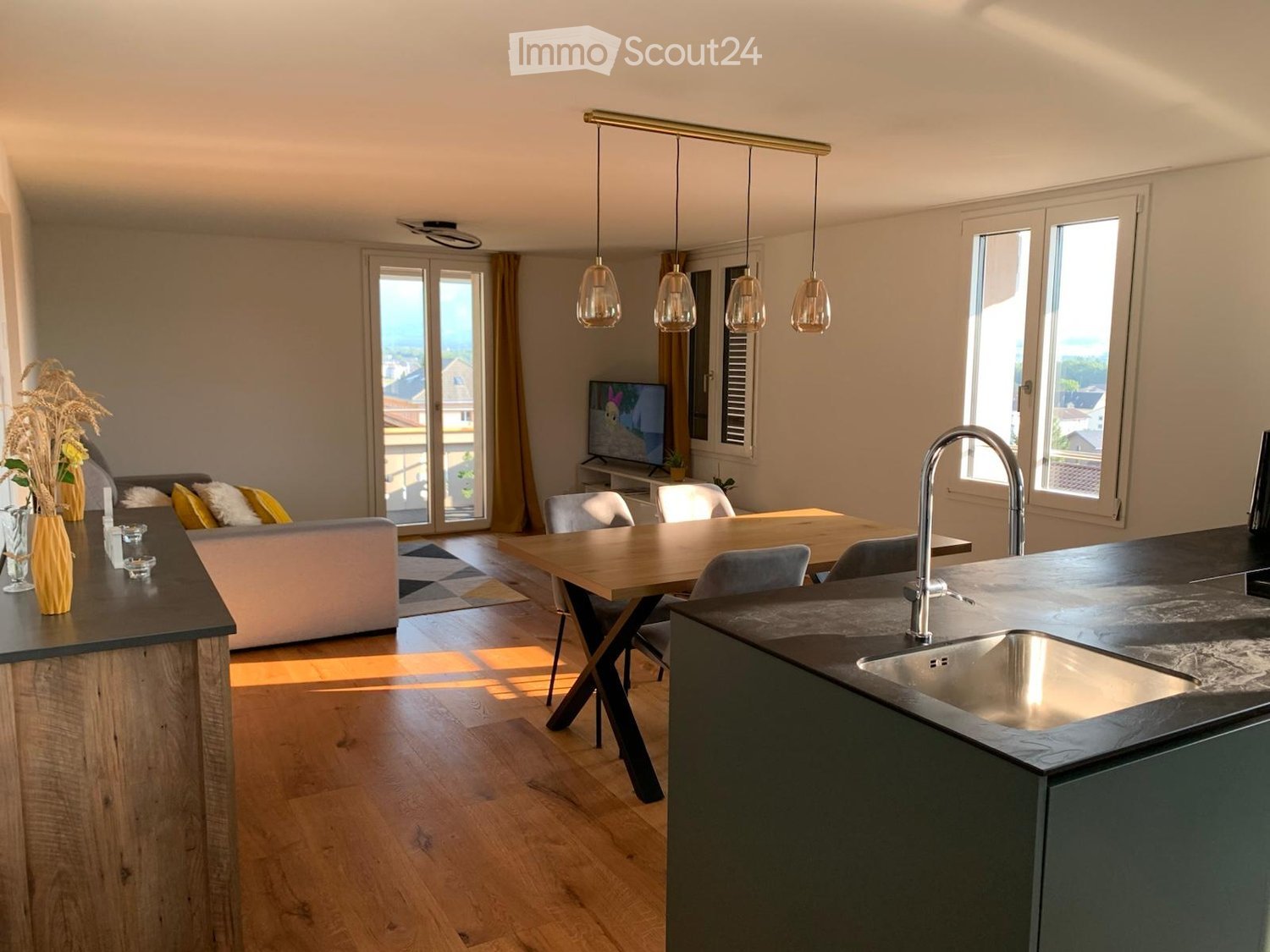 open concept room with a couch, table, chairs, tv, dining area, kitchen island, sink, faucet