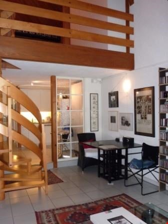 living room with spiral staircase, glass door, white tile floor, black table, 2 chairs, paintings, rug, shelf