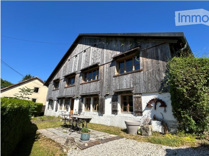 raised ground floor house, wooden exterior, several windows, stone path, outdoor table and chairs, outdoor plants