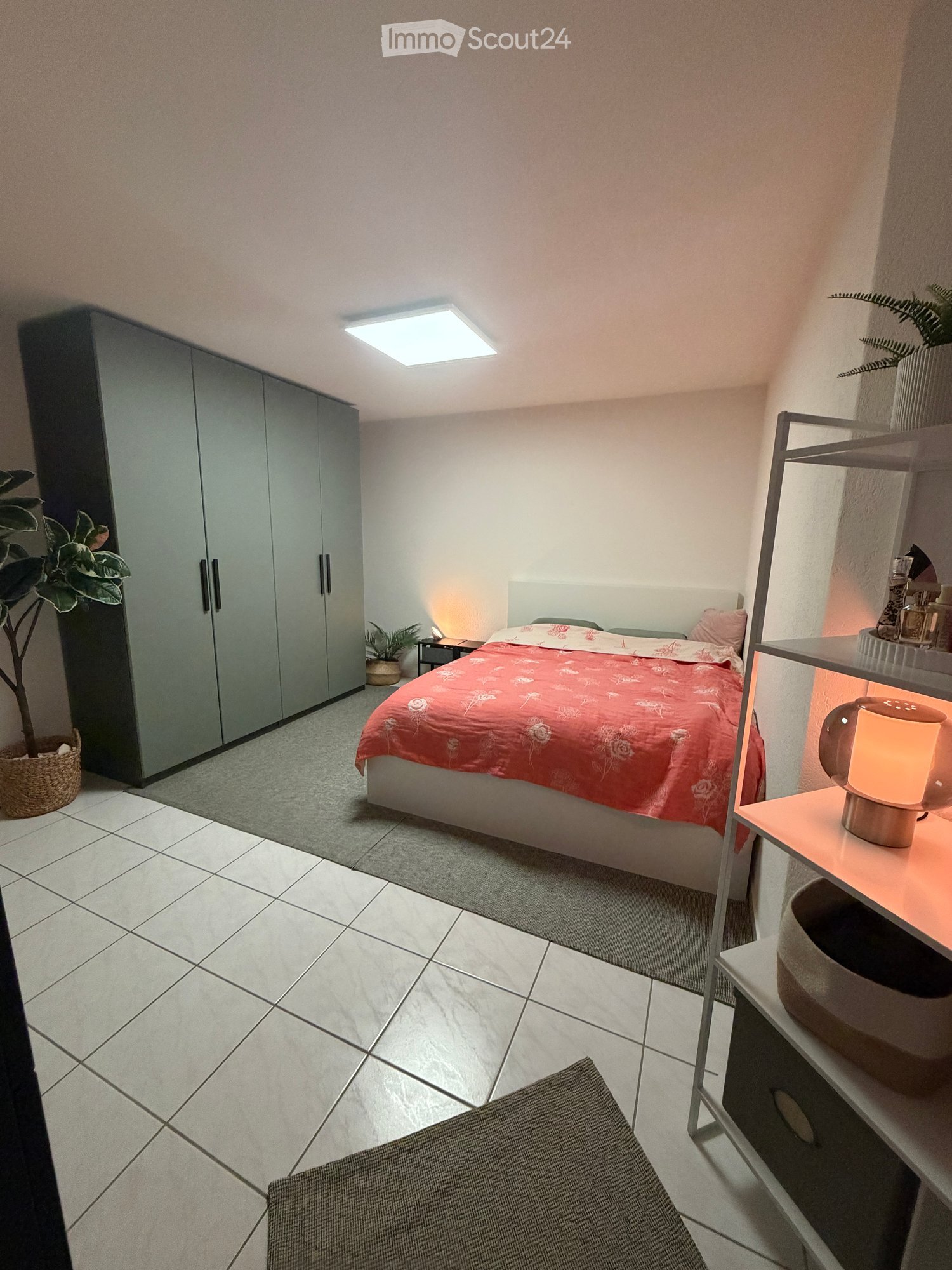 white tiles, grey carpet, large bed, grey wardrobe, nightstand, plants