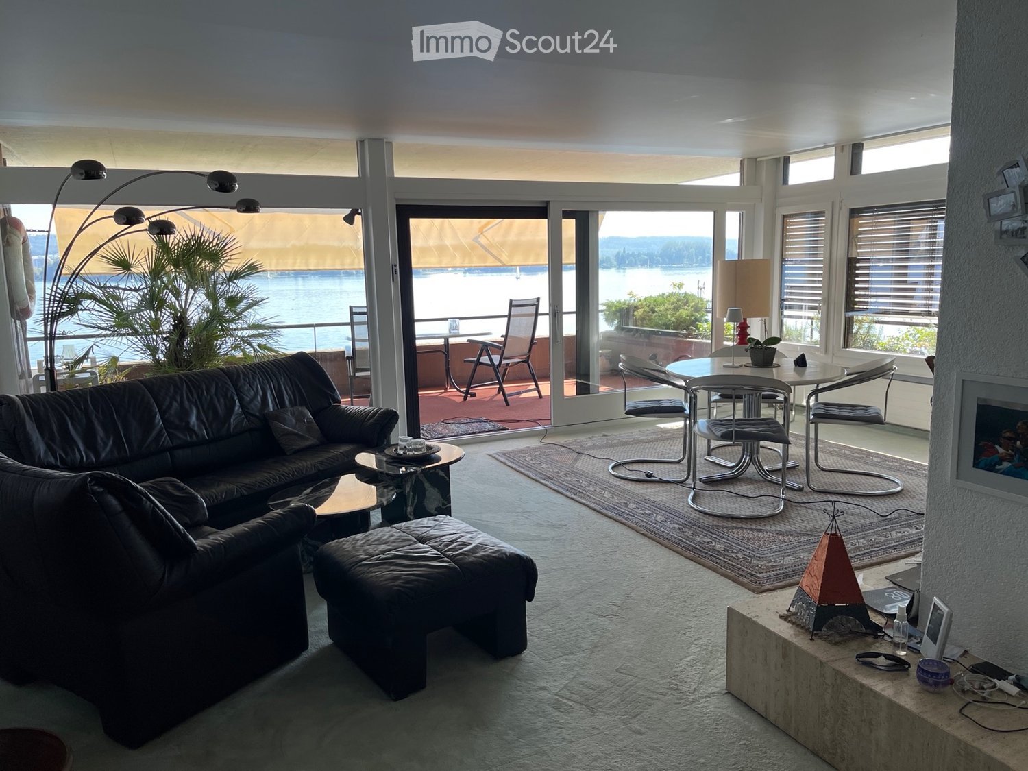 black leather sofa, large rug, dining area with table and chairs, balcony with view