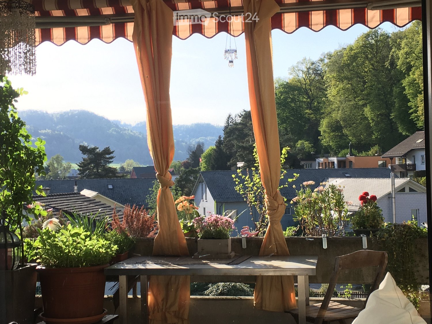 Terrace with table and chairs, flower pots, canopy awnings, string lights