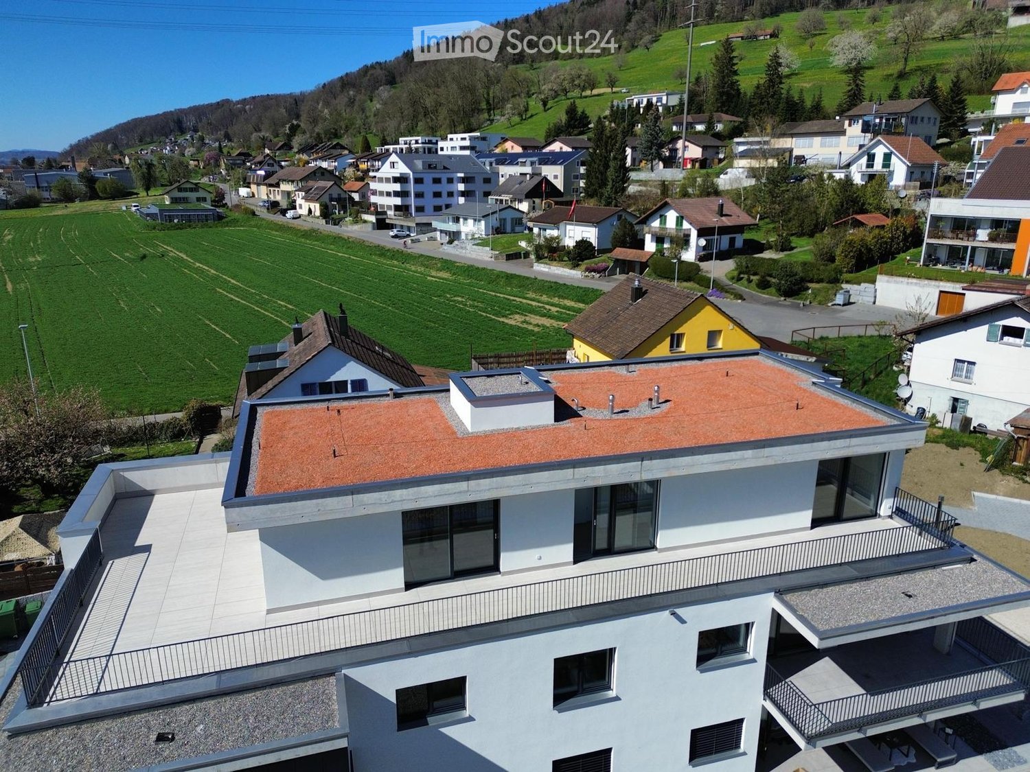 White house, rooftop terrace, large windows, nearby fields, village backdrop, hilly surroundings