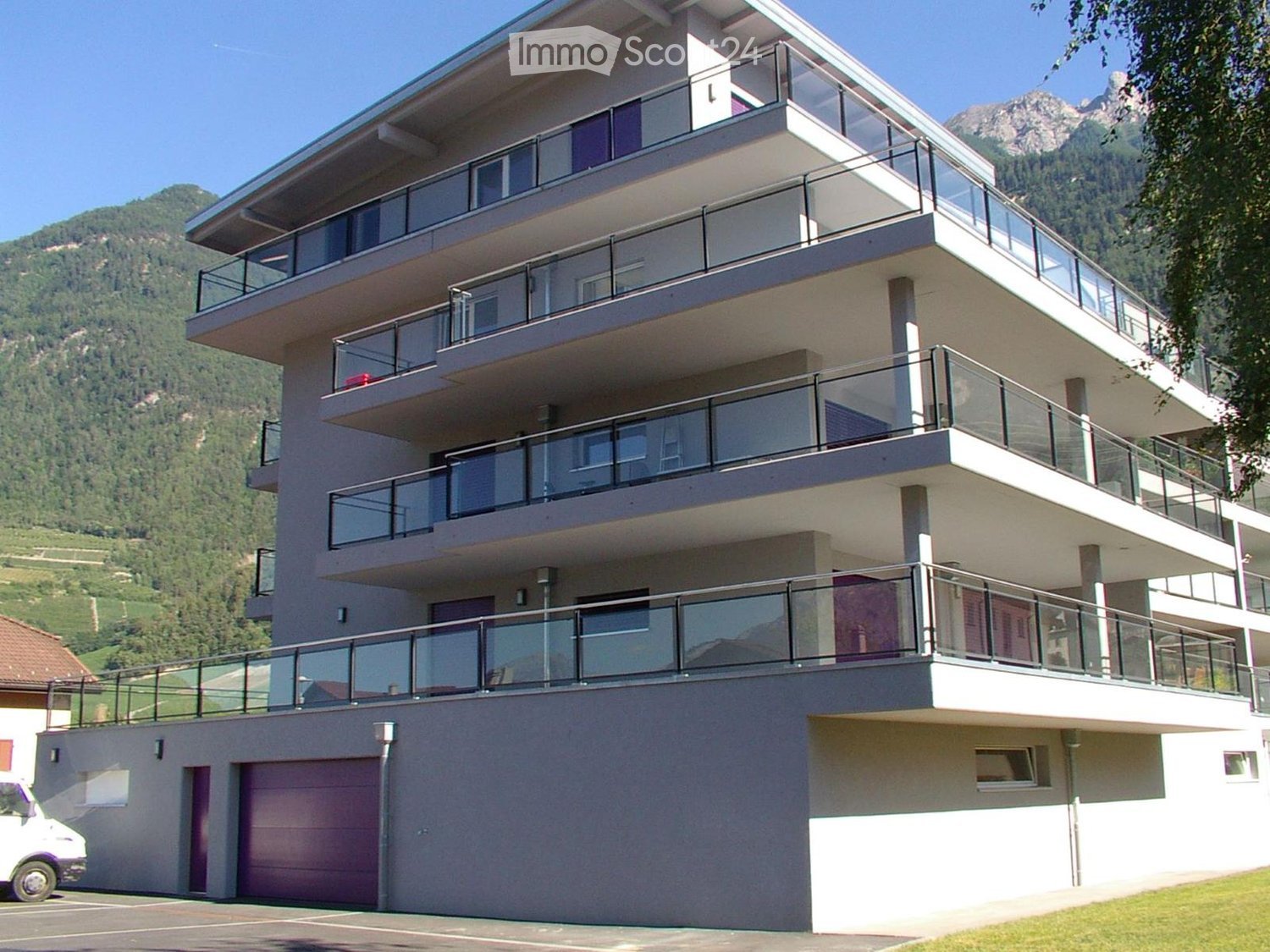Three-story building with multiple balconies and garages