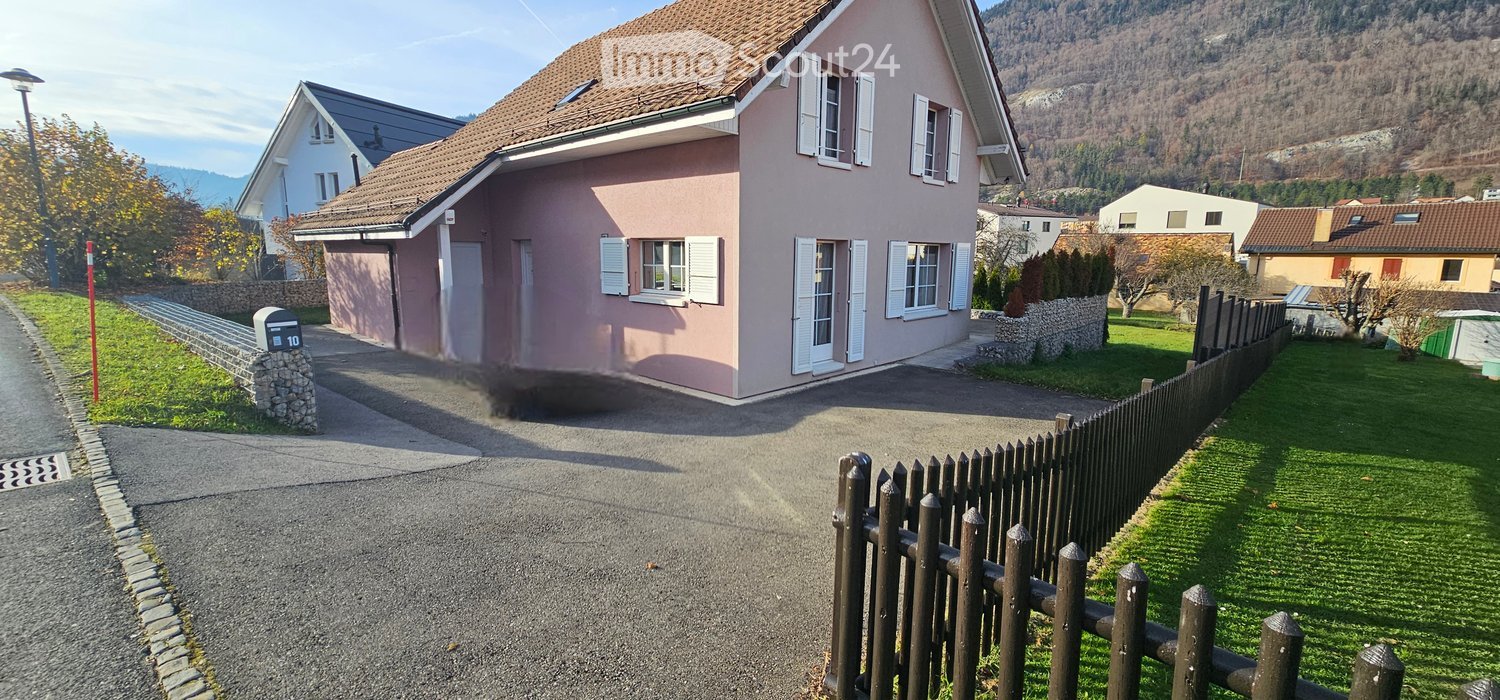 2 story house, pink color, brown roof, windows, mailbox, paved road, wooden fence, well-maintained lawn, driveway, neighboring houses