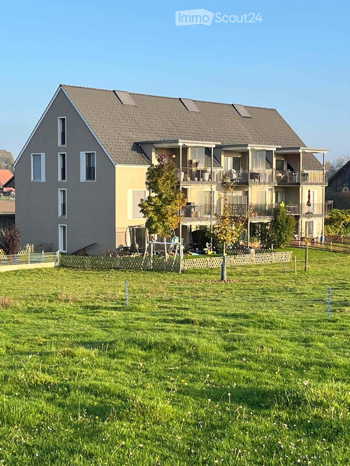 3 story house, gray exterior, windows, balconies on upper floors, green lawn